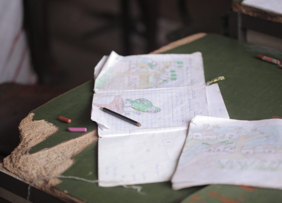 african education - close up of a school kid sitting inside a classroom, holding a pencil, indoors on a sunny day