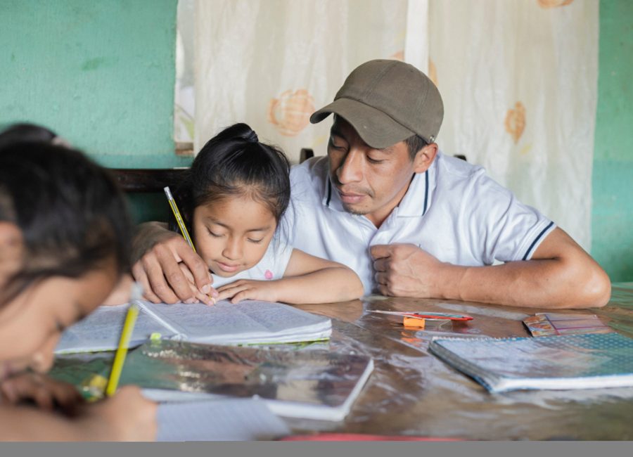Hispanic father helping his daughters do their homework - teacher teaching girls to read and write - Mayan family at home in extracurricular activities